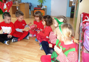 Dzieci siedzą w kole i podają sobie prezent